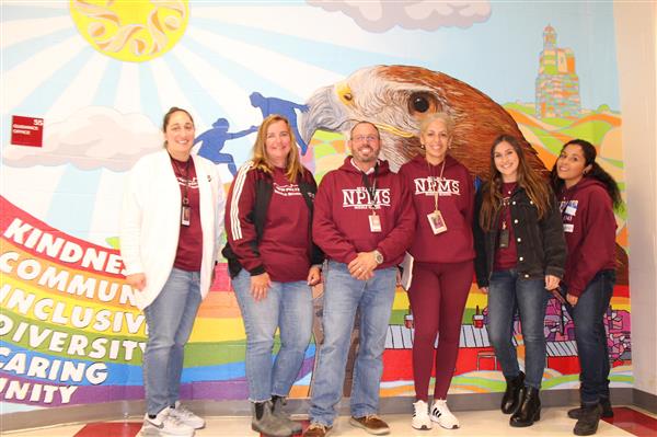  student support staff stands in front of mural 